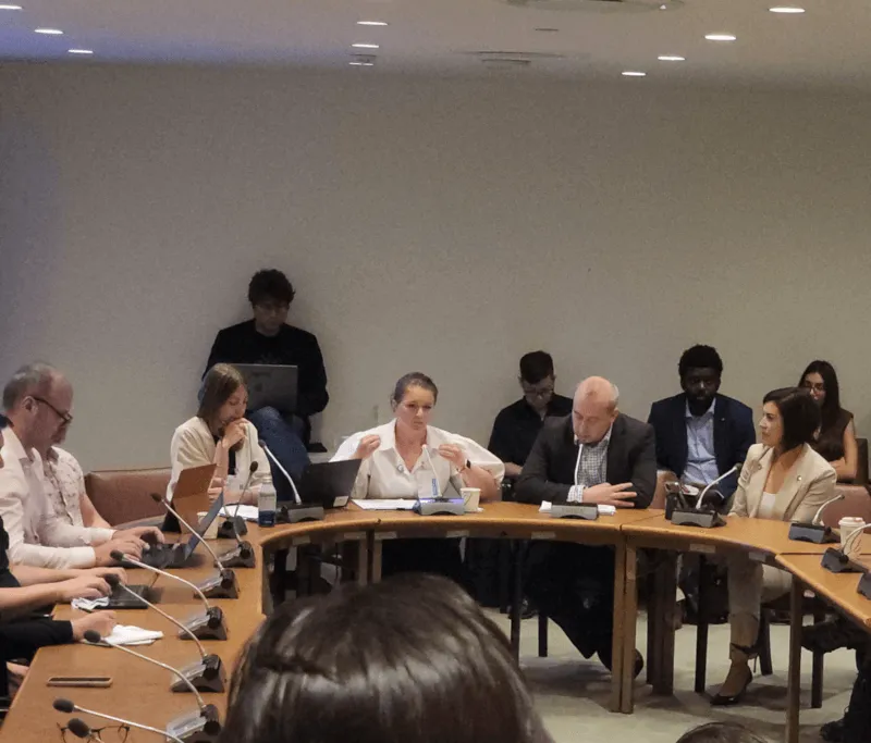 People seated at a table arranged in a semicircle, actively engaged in conversation during Digital Public Infrastructure Day.
